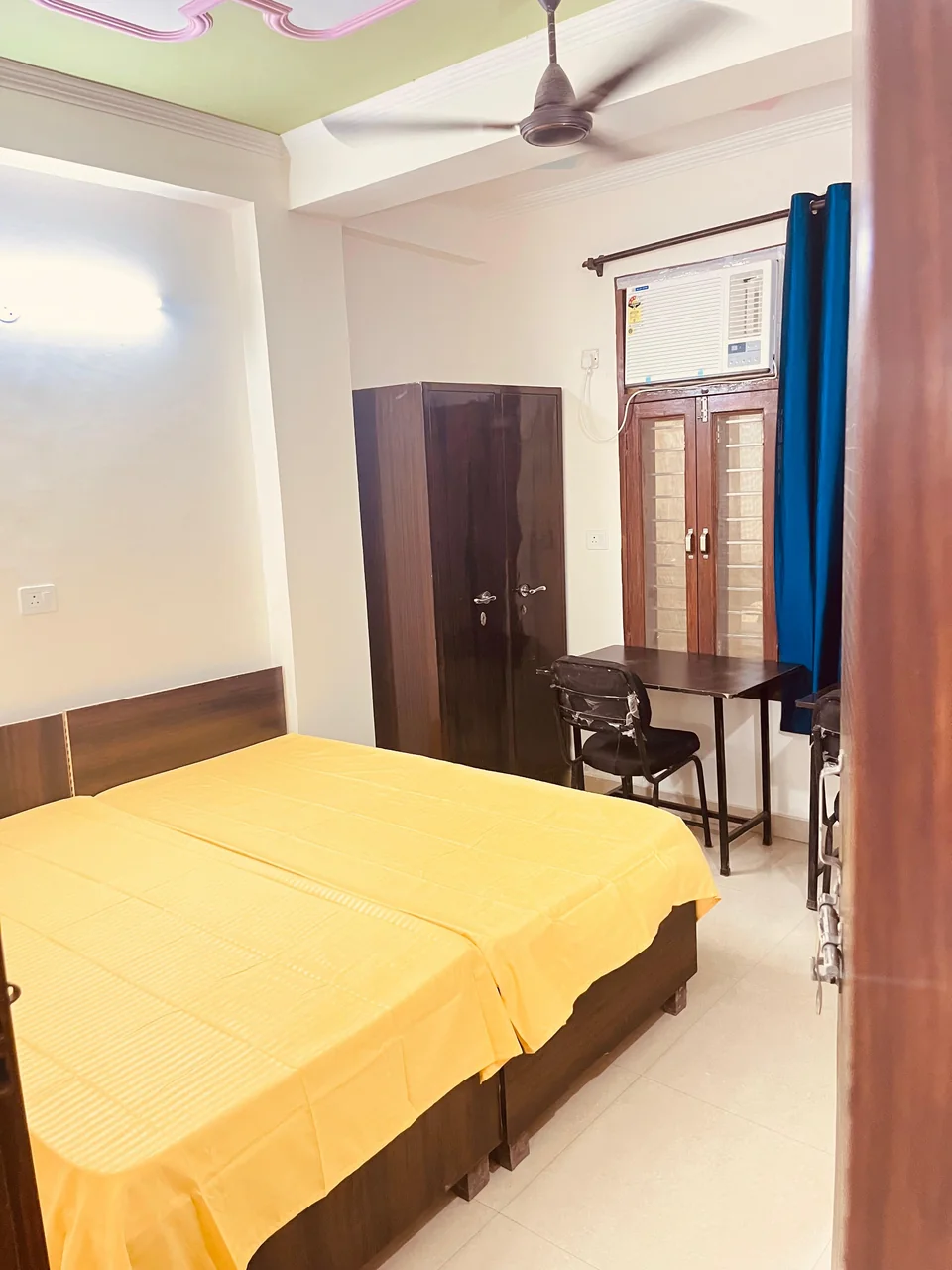 A furnished room with a bed, wardrobe, desk and chair.