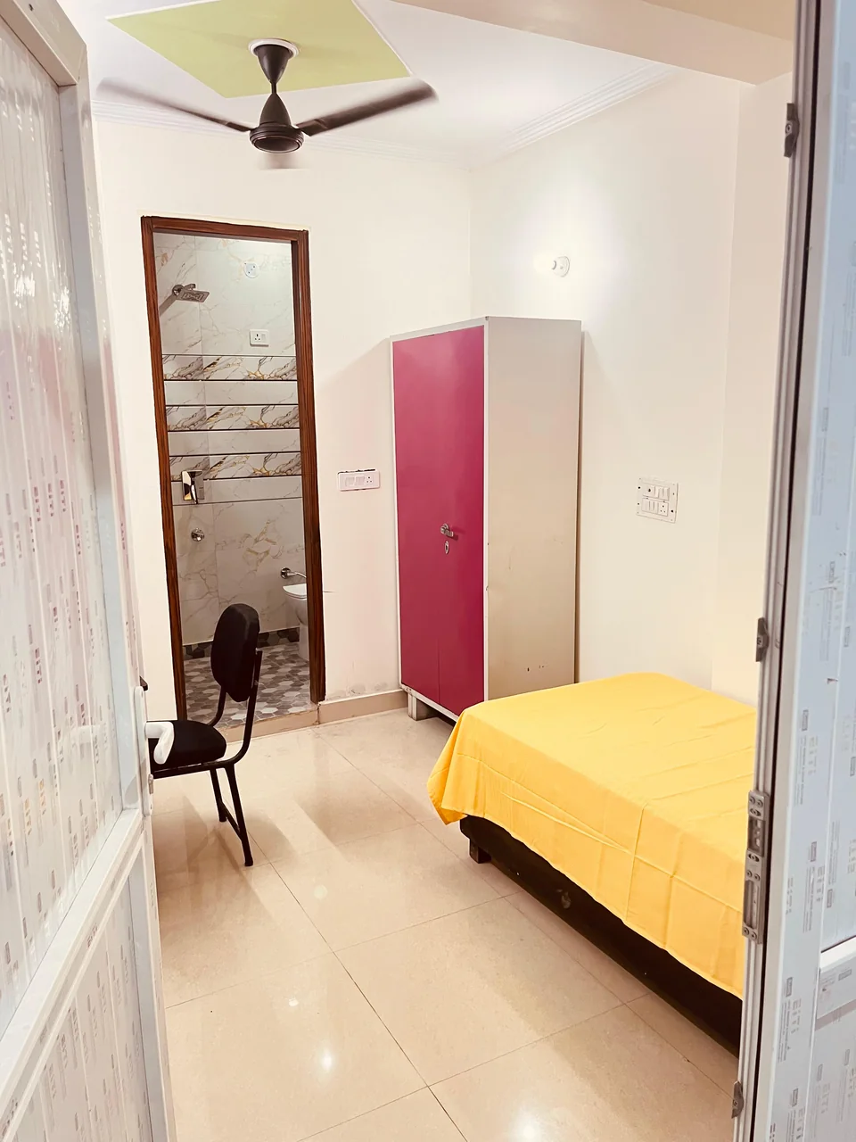 A room with a bed, wardrobe and study desk.